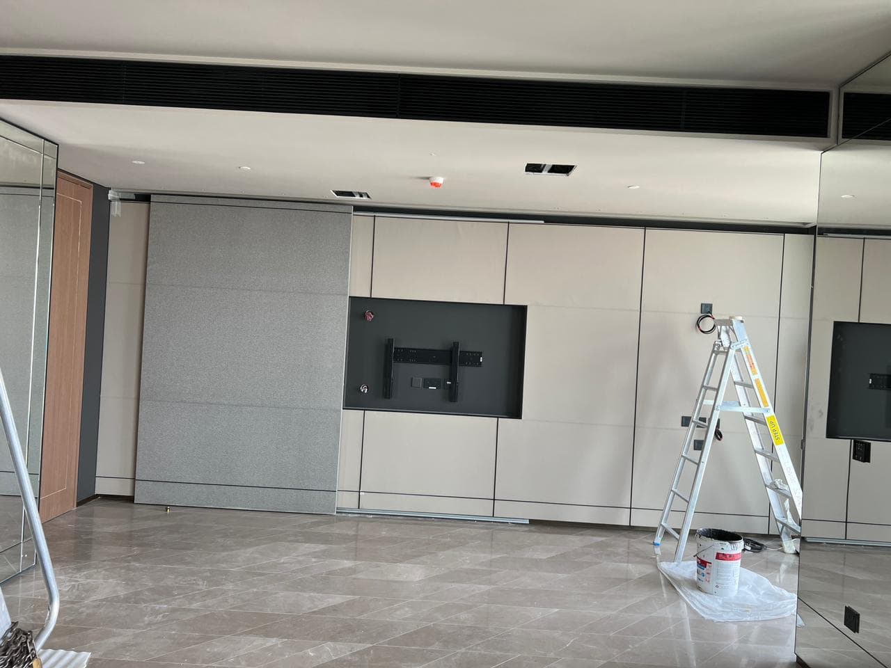 Office feature wall in panelled leather-look finishes with a recessed media niche and marble flooring