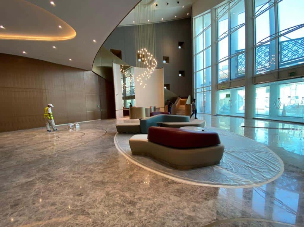 Double-height lobby with grey marble flooring, curved feature walls and a cascading chandelier